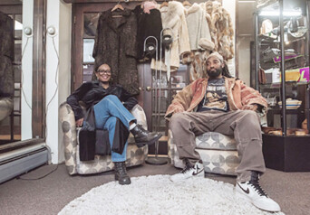 Two people sitting in two chairs inside a shop