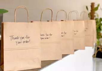 A line of takeout bags on a counter with the message "thank you for your order" on each one