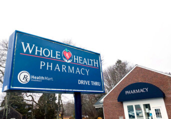 Whole Health Pharmacy brick building and blue sign from outside