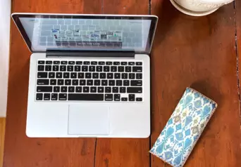 Photo from above of a laptop open on a wooden desk